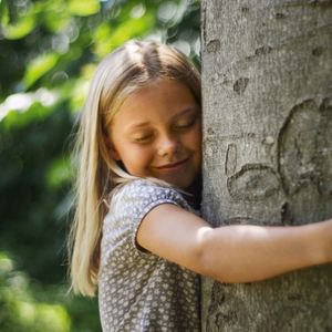 Bambina che abbraccia albero