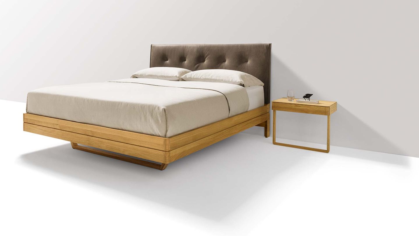Designer bed made of wood with leather headboard